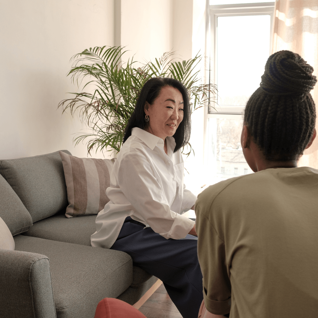 a woman sitting on a couch talking to another woman